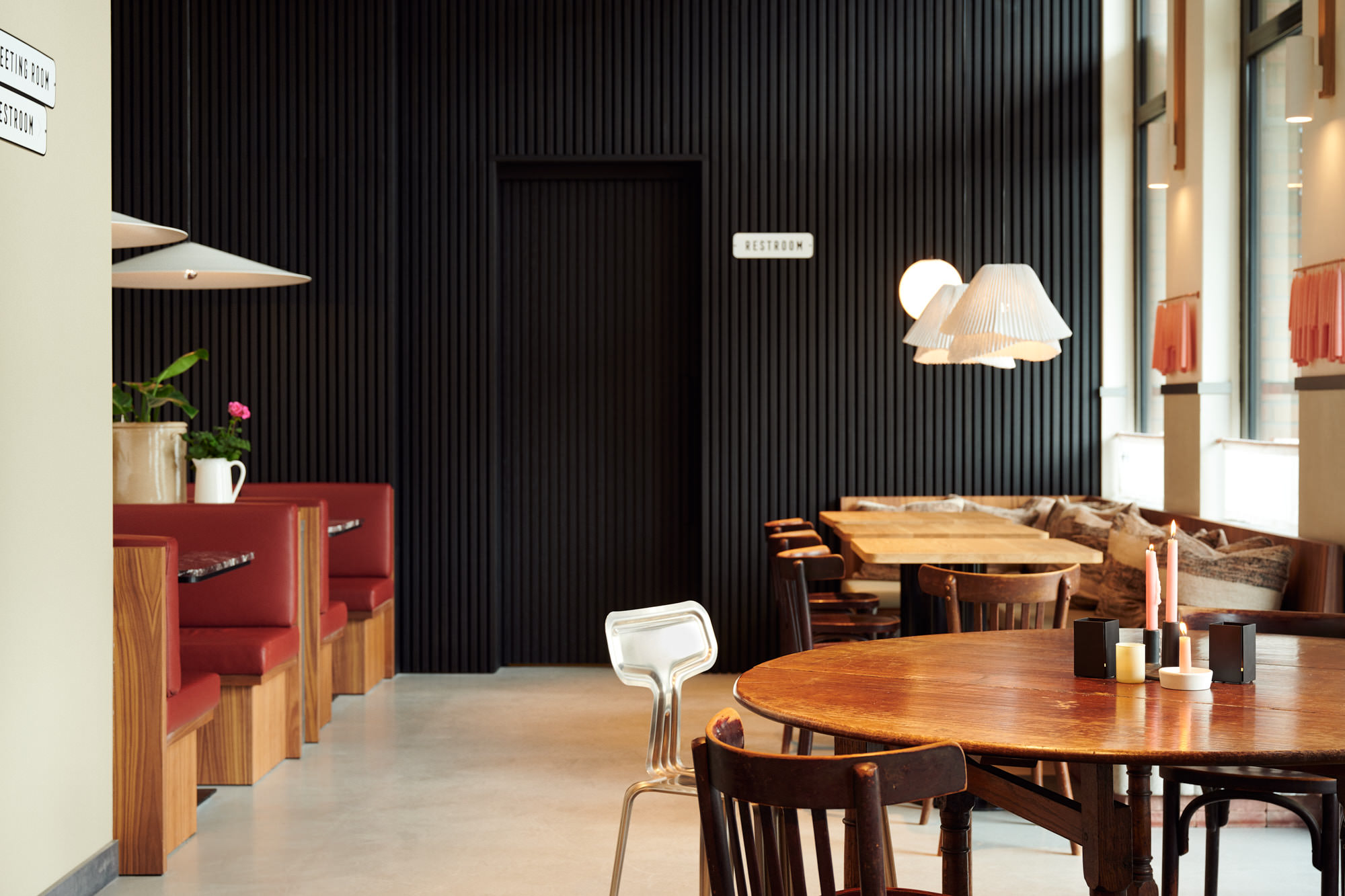 Interieur van The Villy met zwarte lamellenwand, rode banken en ronde houten tafel