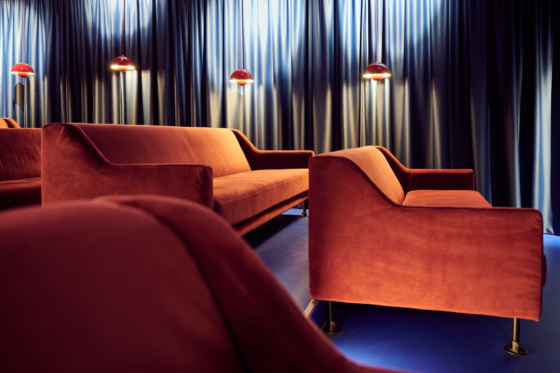 Lounge met dieprode banken en blauwe gordijnen