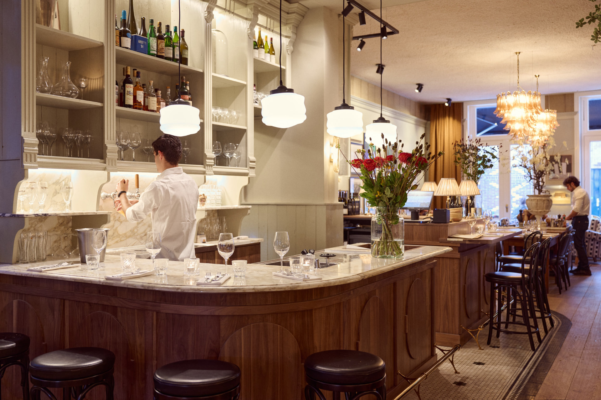 De bar van restaurant Madeleine met houten front en krukken