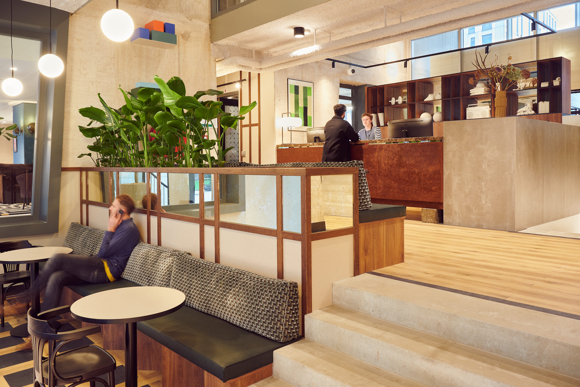 Lounge met zitbank, planten en receptie bij Our Domain Blaak