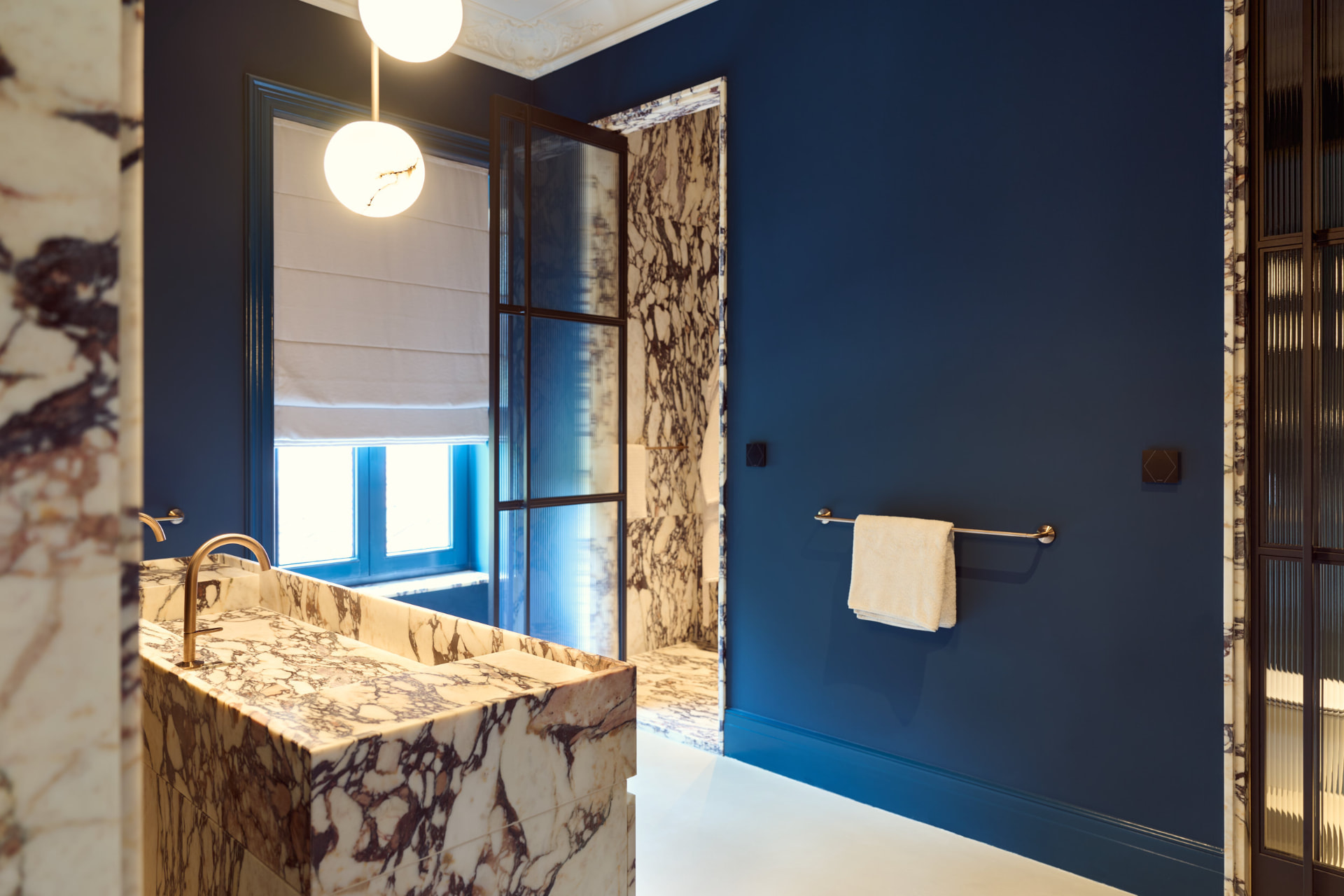 Badkamer met marmeren wastafel en blauwe wand