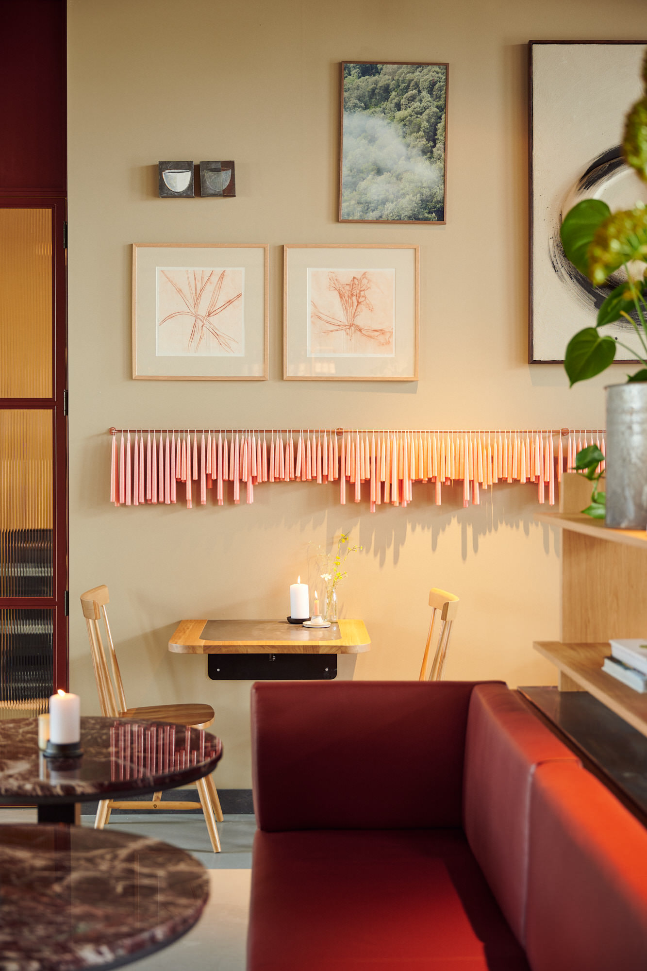 Hoekje van The Villy met rode bank, kleine tafel en kunst aan de muur