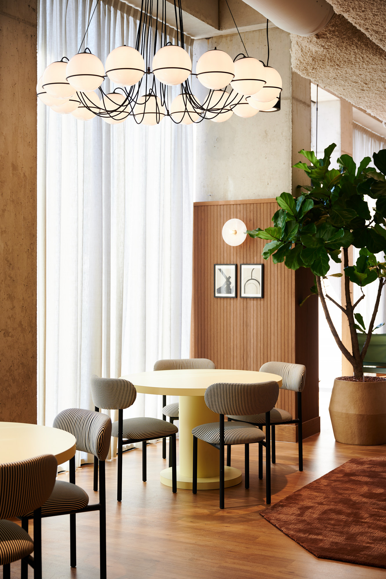Ronde tafel met gestreepte stoelen onder een bollenkroonluchter
