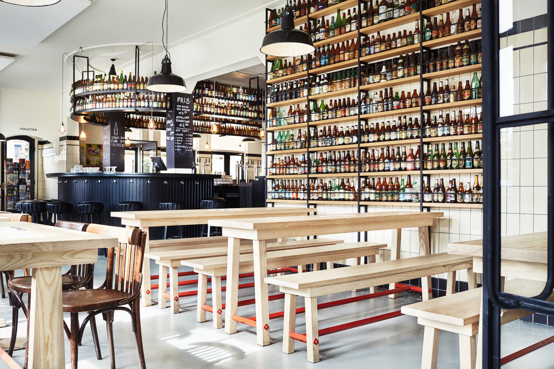 Brouwerij ’t IJ met houten tafels en flessenwand
