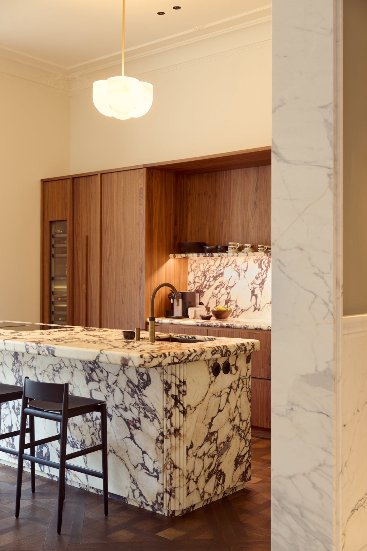 Keuken met marmeren kookeiland en houten kastenwand in een woonhuis