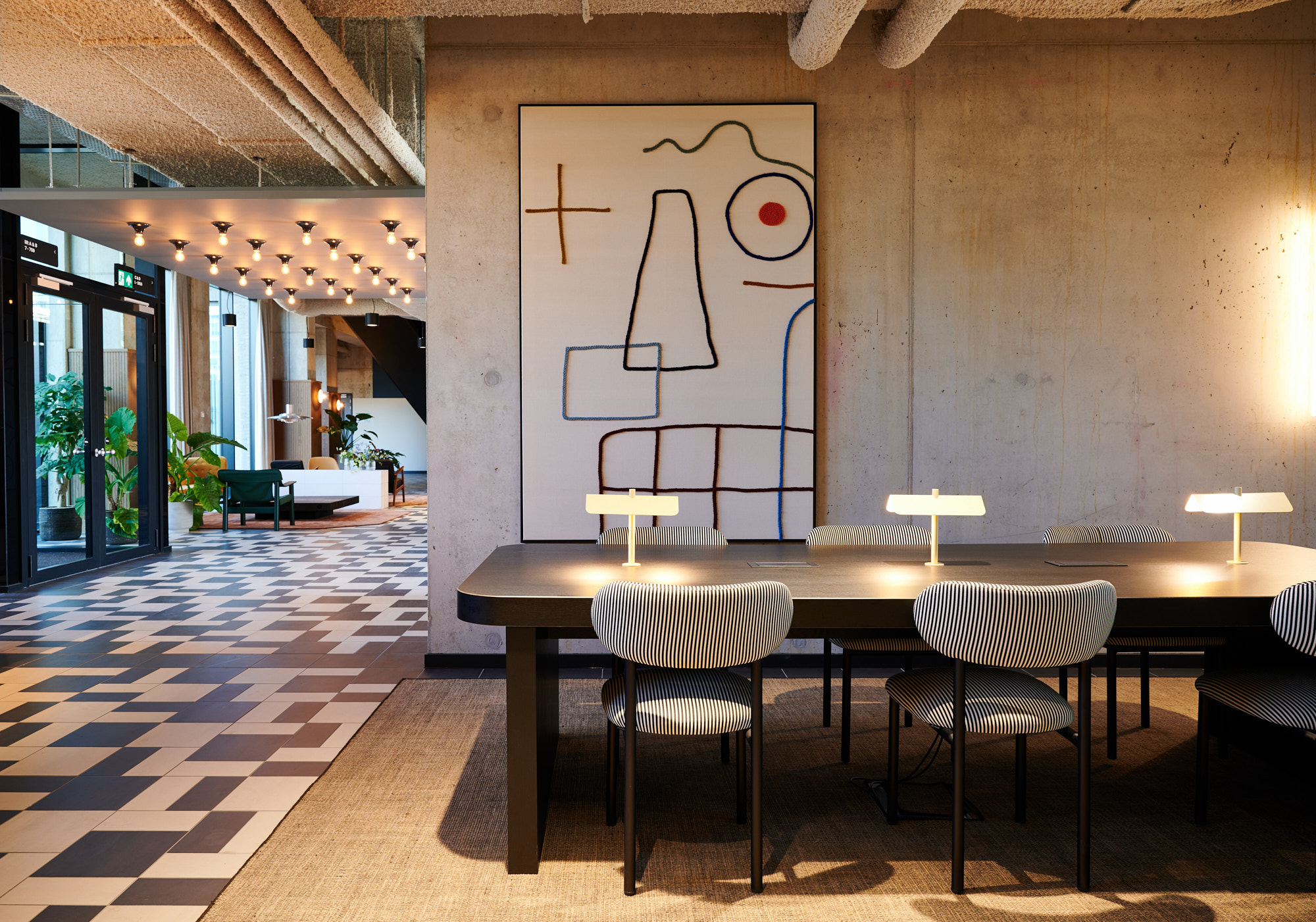 Werktafel met gestreepte stoelen voor een groot wandkunstwerk